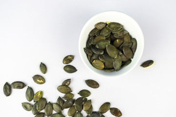 A cup with pumpkin seeds on white background with copy space