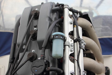 Obraz premium Close up rear side of boat transom four stroke 4 cylinder fuel injection outboard motor - fuel pump, fuel filter, fuel rail with injectors, intake manifold, high voltage wires, maintenance service
