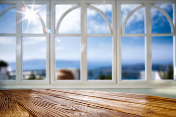 Window and wooden table background and sunny beach in distance.