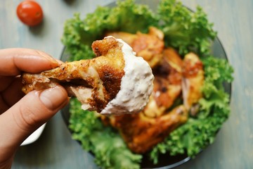 Chicken wings and lettuce and tomato. Chicken wing dipped in sauce. Meat in sour cream sauce. © Anastasiia K.