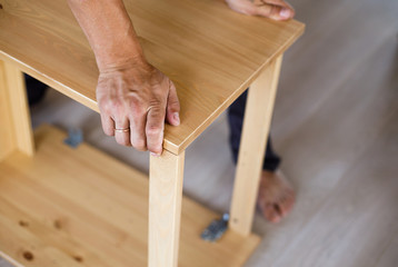 Man assembling wooden furniture at home, close up image