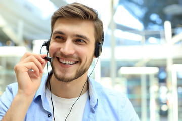 Smiling friendly handsome young male call centre operator.