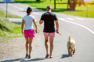 Obraz premium Man and woman walking with a dog in the Park 