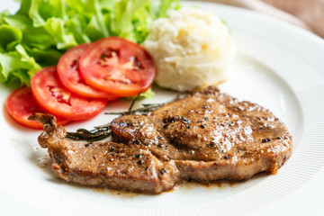 Pork chop steak with mash potato in white plate.