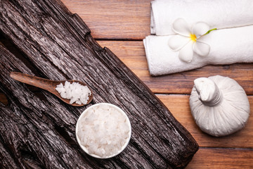 Spa aromatic sea salts, and herbal massage ball on wooden background.