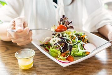 Eat green concept with organic fresh vegetable salad in ceramic plate on wooden background.