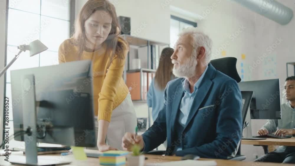 Poster Handsome Middle Aged Creative Engineer Sitting at the Desk working on Desktop Computer Has Discussion with Beautiful Female Project Manager. Office with Friendly Colleagues Chatting, Finding Solutions