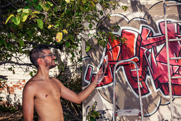 Graffiti artist painting a wall in the street