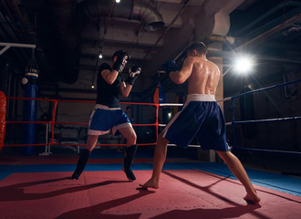 Martial man boxer exercising kickboxing with sparring partner in the ring at the sport club