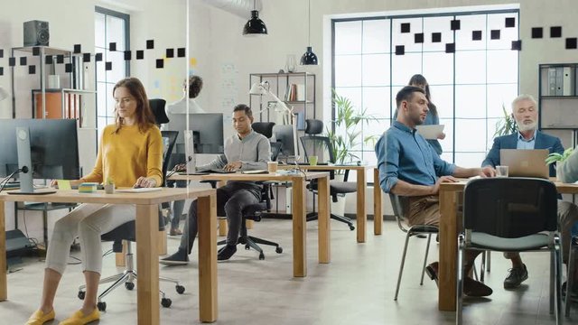 In the Stylish Open Space Office: Diverse Group of Enthusiastic Business Marketing Professionals Use Computers, Have Meetings, Discussing Project Ideas, Brainstorming Startup Company Strategy