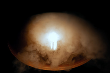 light bulb in smoke on black background