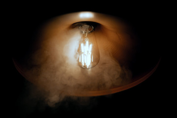 light bulb in smoke on black background