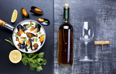 Flat-lay mussels in white sauce and wine bottle