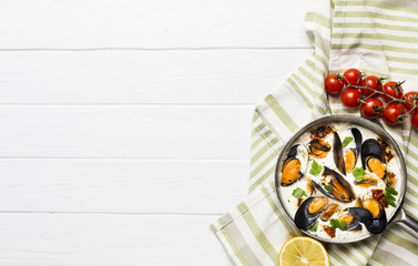 Flat-lay mussels in white sauce and sides on tablecloth with copyspace