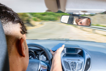 Naklejka premium Young driver, using smartphone, on the road in the car.