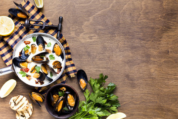 Flat-lay mussels in white sauce on tablecloth with copyspace