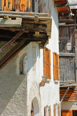 Fototapeta na wymiar Close-up on traditional wooden houses in Saint Veran village with a white statue of virgin Mary in the foreground, Queyras Regional Natural Park, Southern Alps, France