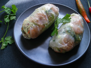 Fresh summer rolls (nem song) on a plate decorated with coriander and peppers