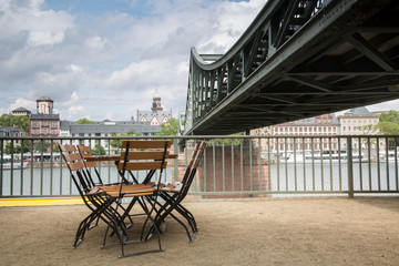 Fototapeta na wymiar Eiserner Steg Bridge with Cafe Table and Chair; Frankfurt