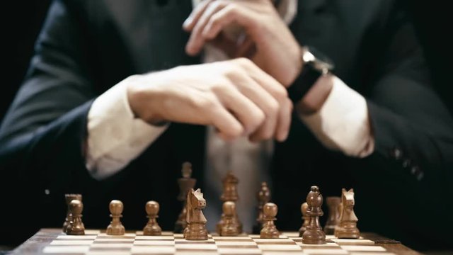 partial view of businessman sitting at table and playing chess