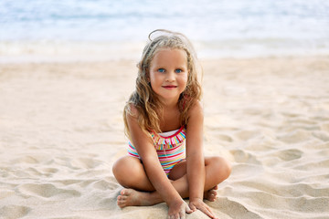 Happy cute child playing on sandy beach.