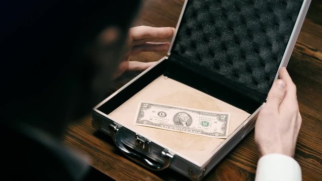 cropped view of businessman opening briefcase with dollar banknote on wooden surface