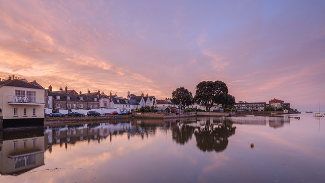 Soft dawn sky over riverside properties with a mirror calm River Exe at Topsham, Devon