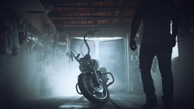 biker with a motorcycle in an atmospheric garage. a man sits on his iron horse and prepares to set off