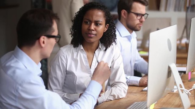 Mixed race employee receive instructions from caucasian mentor at workplace