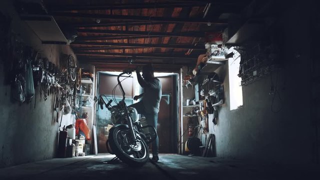 biker with a motorcycle in an atmospheric garage. a man sits on his iron horse and prepares to set off