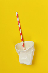 Single-use plastic problem - used plastic glass and drinking straw on the colorful background	