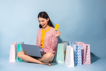 Asian woman shopping online at home on Blue background