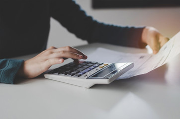 hand of young woman using calculator for analysis and calculating family budget cost bills on desk...