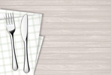 Fork and table knife on a napkin. Wooden table.