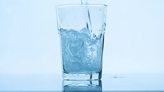 Poring carbonated soda water in drinking glass, slow motion