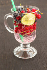 Glass with a cooling drink of berries and ice. Air bubbles on glass. Black background.