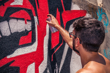 Graffiti artist painting a wall in the street