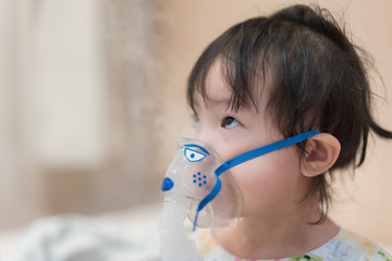 Little asian girl having a medical inhalation treatment with a nebulizer at the hospital.