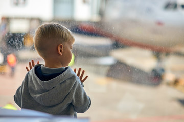 Two year old boy at the airport looking at plane