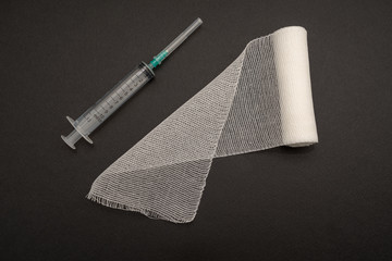 Medical syringe and bandage on black background, health and vaccination concept.