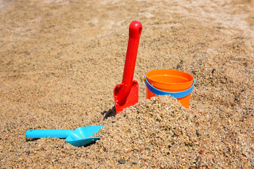 Bright plastic сhildren's beach toys - bucket and shovels on sand near sea