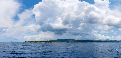 View of the shore from the sea. Panorama with the sea and stormy clouds in the sky