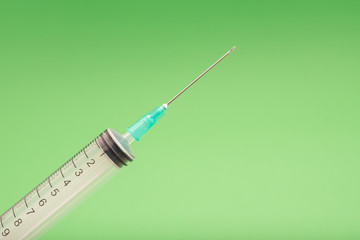 Medical syringe on green background, health and vaccination concept.