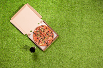 One white open paper box of pizza with glass of red wine on the grass. Concept. Top view.  Copy space