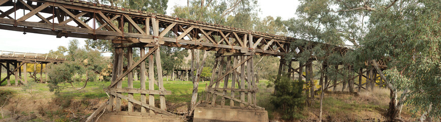 Fototapeta na wymiar old timber hardwood discontinued railway bridge river crossing in a rural farming town, Victoria, Australia