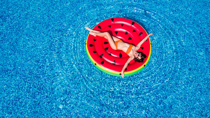 Young beautiful girl in a white bikini air mattress swims in the pool of a luxury hotel top view