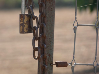 Candado y cadena que protegen la entrada del campo. Puerta protegida por una cadena y un candado