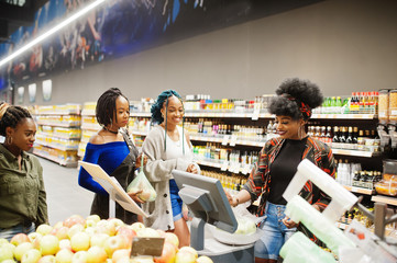Group of african womans weighs apples in polyethylene bags at supermarket.