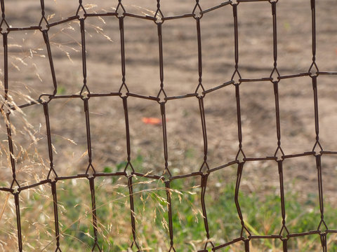 Reja en el campo, la reja est&aacute; hecha de los muelles de un somier. Reja r&uacute;stica para proteger la cosecha.
