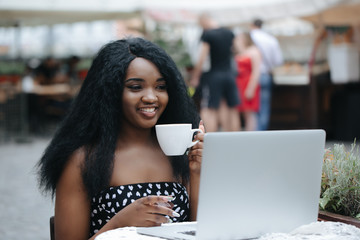 Charming woman with beautiful smile reading good news on laptop during rest in coffee shop, happy ethnic female  relaxing in cafe during free time.